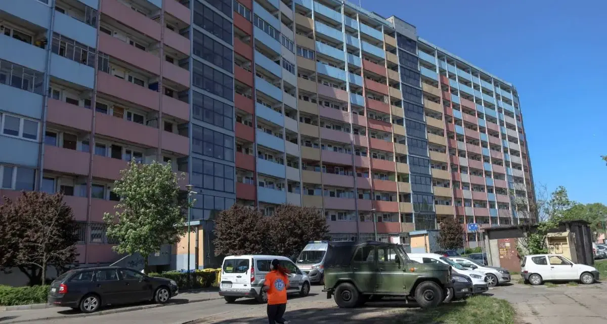 Długi, wielopiętrowy blok mieszkalny, prawdopodobnie najdłuższy blok w Polsce, z kolorowymi balkonami i oknami, na tle błękitnego nieba.