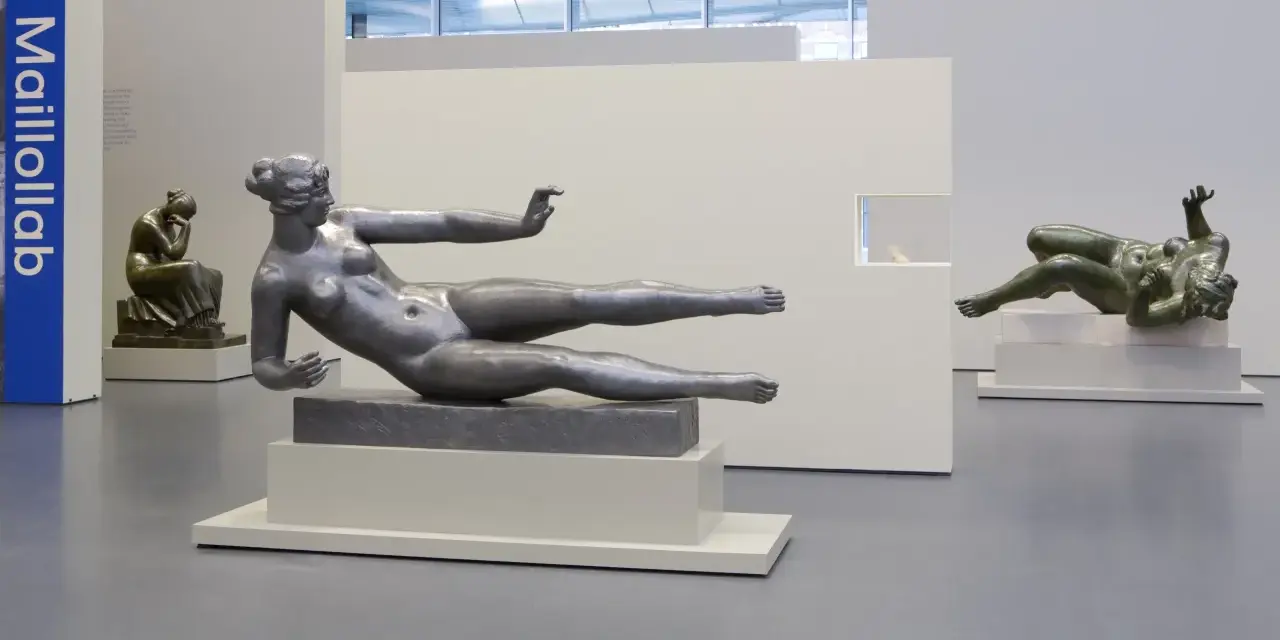 Exposition d'œuvres d'art de Aristide Maillol : sculptures de femmes nues en bronze et en métal, dans un musée.