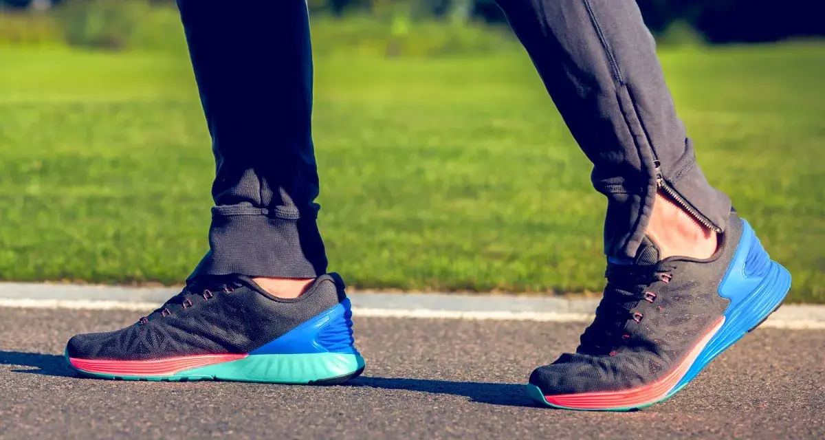 Biegacz stawia kroki, a jego stopa wykonuje ruch supinacji. Kolorowe buty sportowe na bieżni.