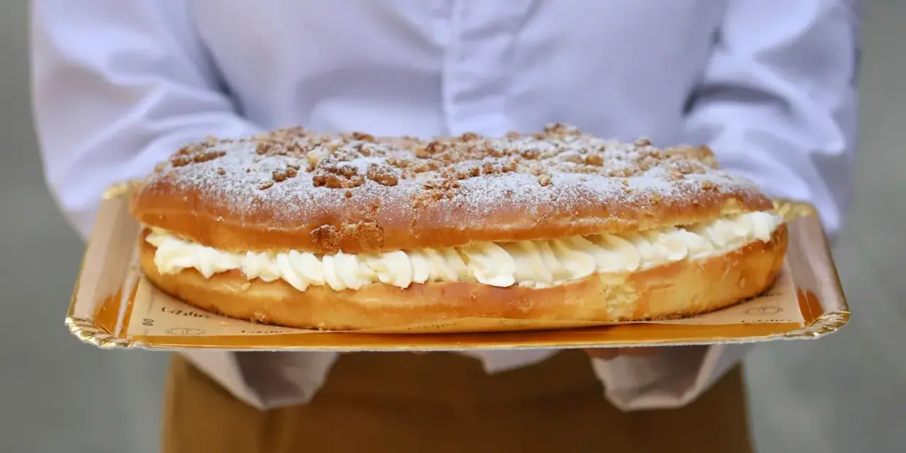 Deliciosa coca de San Juan rellena de crema, cubierta con azúcar glas y trocitos crujientes. ¡Perfecta para celebrar!
