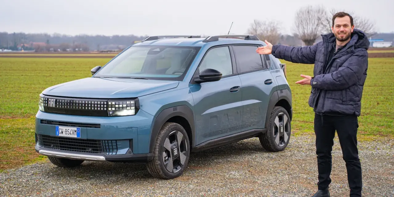 Mężczyzna prezentuje nowy, niebieski Fiat Grande Panda na tle zielonego pola.