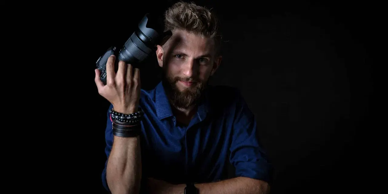 Mężczyzna z aparatem fotograficznym, gotowy do rozpoczęcia kursu fotografii.