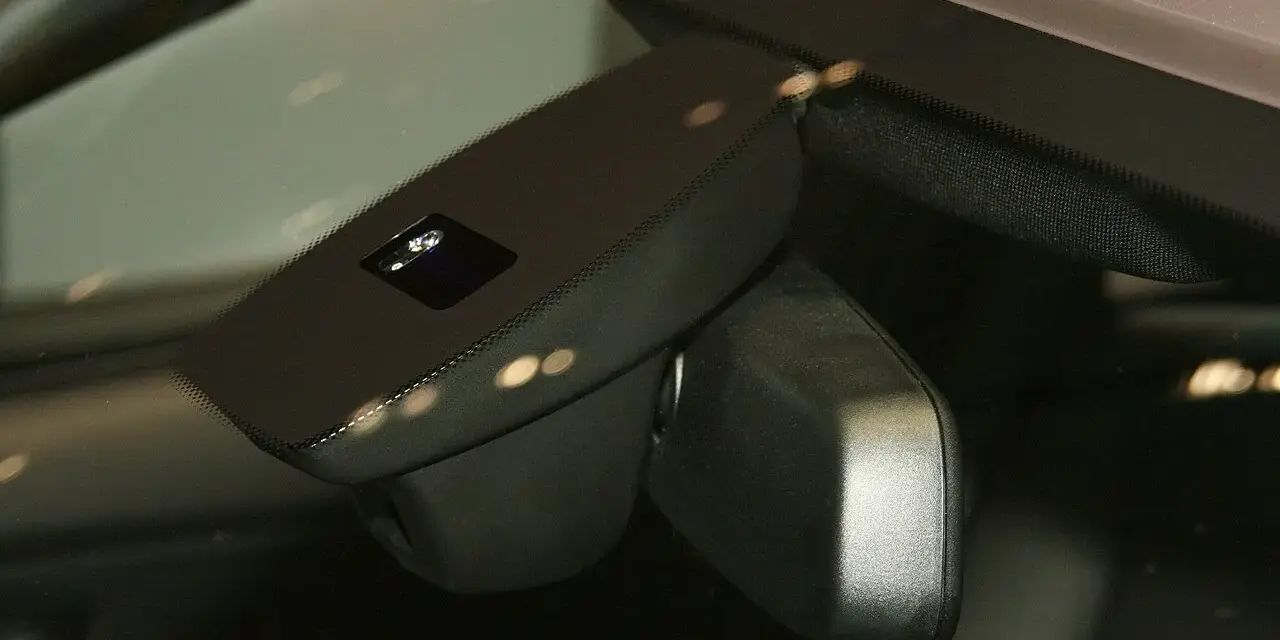Nahaufnahme eines Regensensors im Auto, der die Windschutzscheibe überwacht, um bei Regen die Scheibenwischer zu aktivieren.