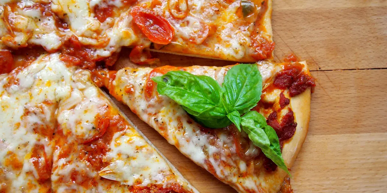 Szybki przepis na ciasto do pizzy: pyszna, domowa pizza z pomidorami i mozzarellą, ozdobiona świeżą bazylią.