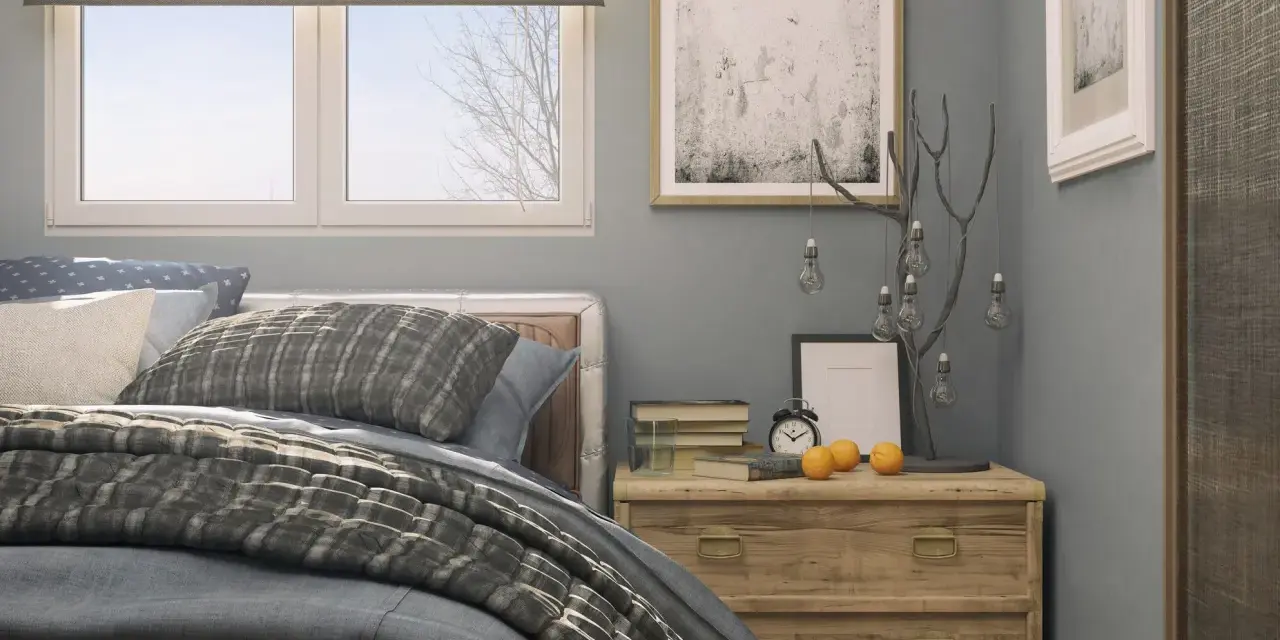 Ideas para decorar una habitación: cama con textiles grises, mesita de noche de madera con adornos y cuadros en la pared.