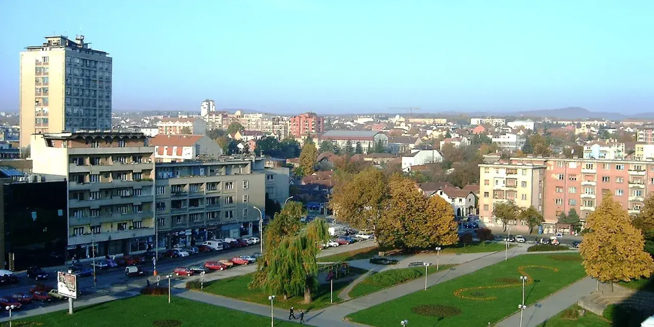 Widok na centrum Kragujevac Serbia z budynkami mieszkalnymi, parkiem i ulicą pełną samochodów.