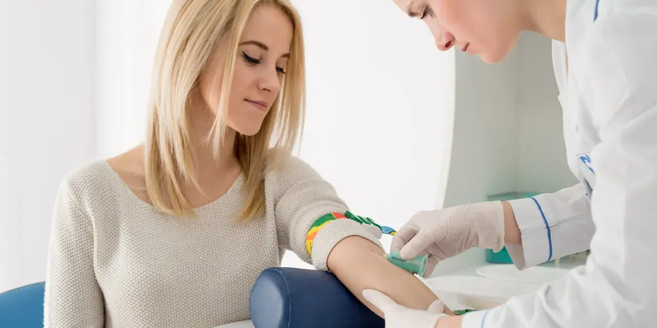 Pielęgniarka pobiera krew od pacjentki. Wyniki badań wskazują na rdw-cv podwyższone, co może sugerować niedobór żelaza.
