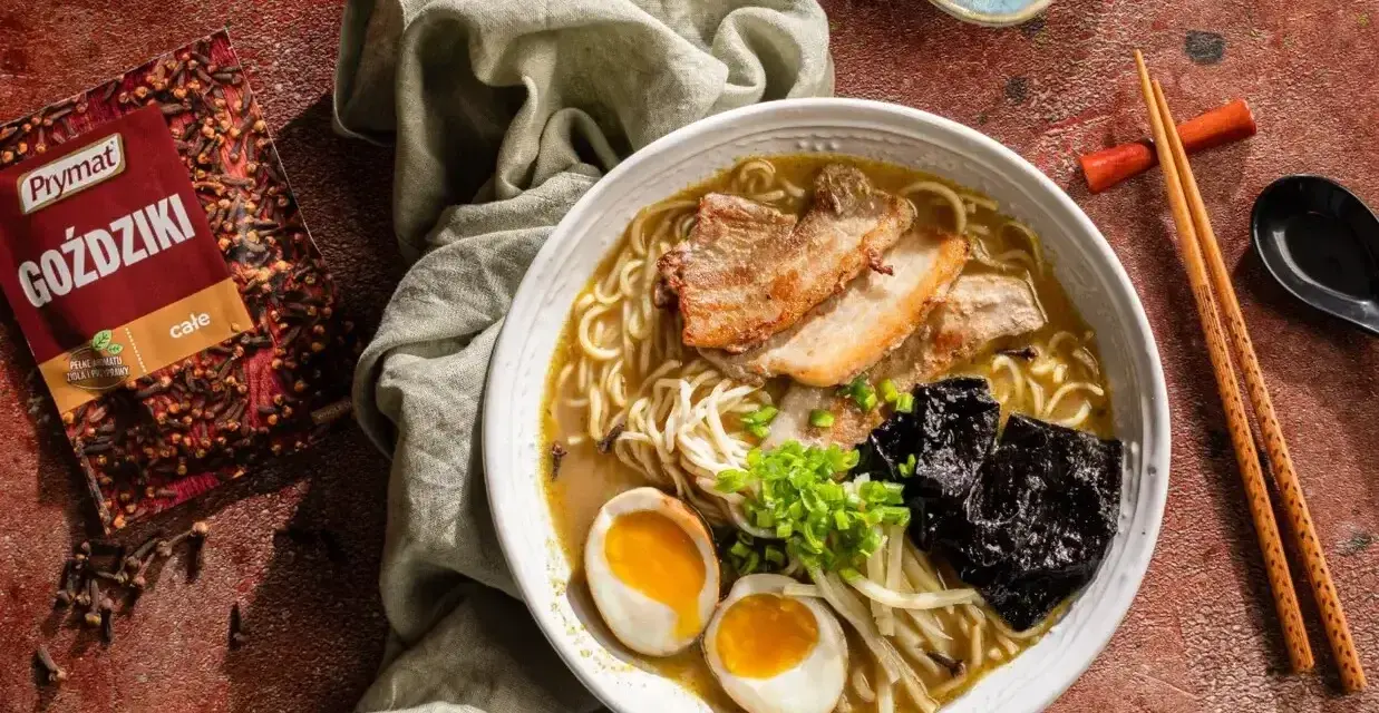 Jak zrobić ramen? Aromatyczny bulion, makaron, jajko na pół, plastry mięsa i nori. Obok paczka goździków Prymat.