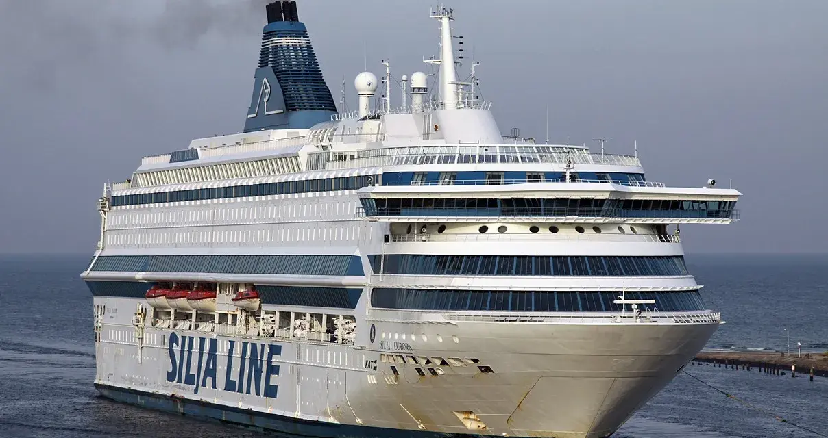 Ogromny prom pasażerski Silja Europa z charakterystycznym kominem i niebieskimi pasami na białym kadłubie płynie po spokojnym morzu.