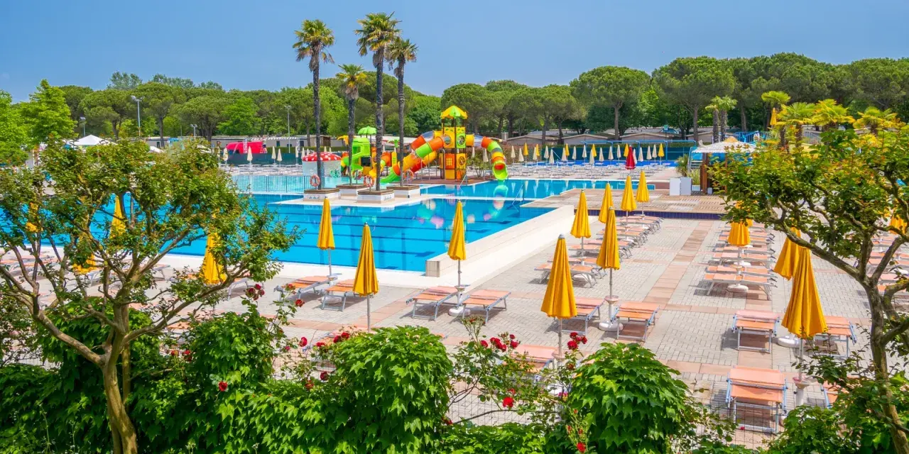 Słoneczny dzień w Portofelice Camping Village. Baseny, zjeżdżalnie i leżaki czekają na gości.