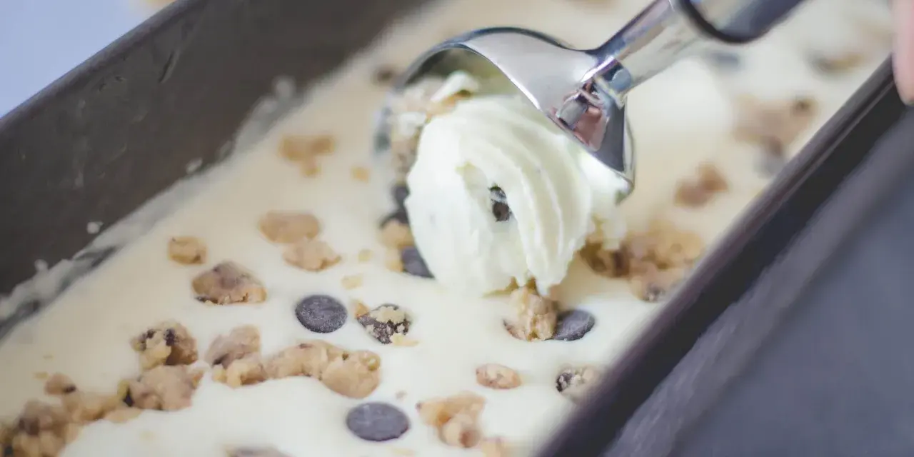 Mit einem Eisportionierer wird cremiges Cookie Dough Eis mit Schokostückchen aus einer Form gehoben. Perfekt, um Eis selber machen zu erleben!