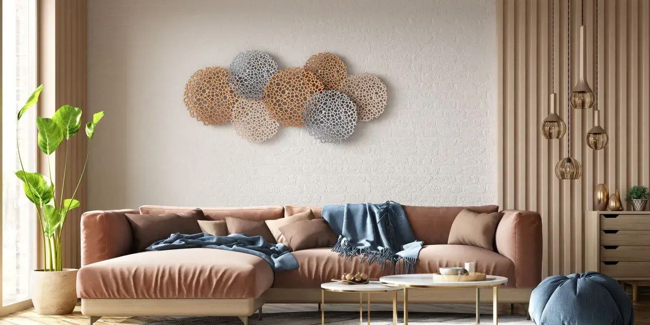 Decoración pared salón original con un sofá terracota y arte de pared circular en tonos dorados y plateados.