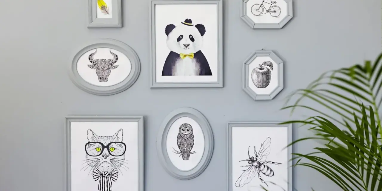 En samling gråa ramar med djur och föremål. En panda med fluga, en tjur, en katt med glasögon, en uggla, en bi, ett äpple och en cykel. Någon har valt att måla ramar för att skapa en personlig vägg.