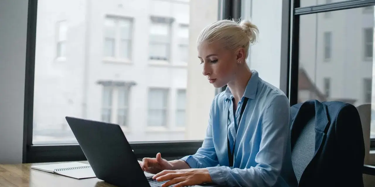 Donna bionda lavora al laptop, analizzando dati per ottimizzare lo stipendio dell'e-commerce manager.
