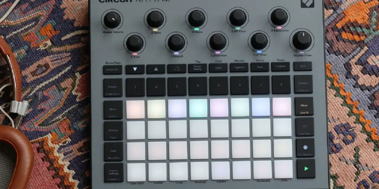 Szary kontroler Circuit Rhythm z podświetlanymi padami, gotowy do tworzenia muzyki. Słuchawki obok dopełniają scenę.