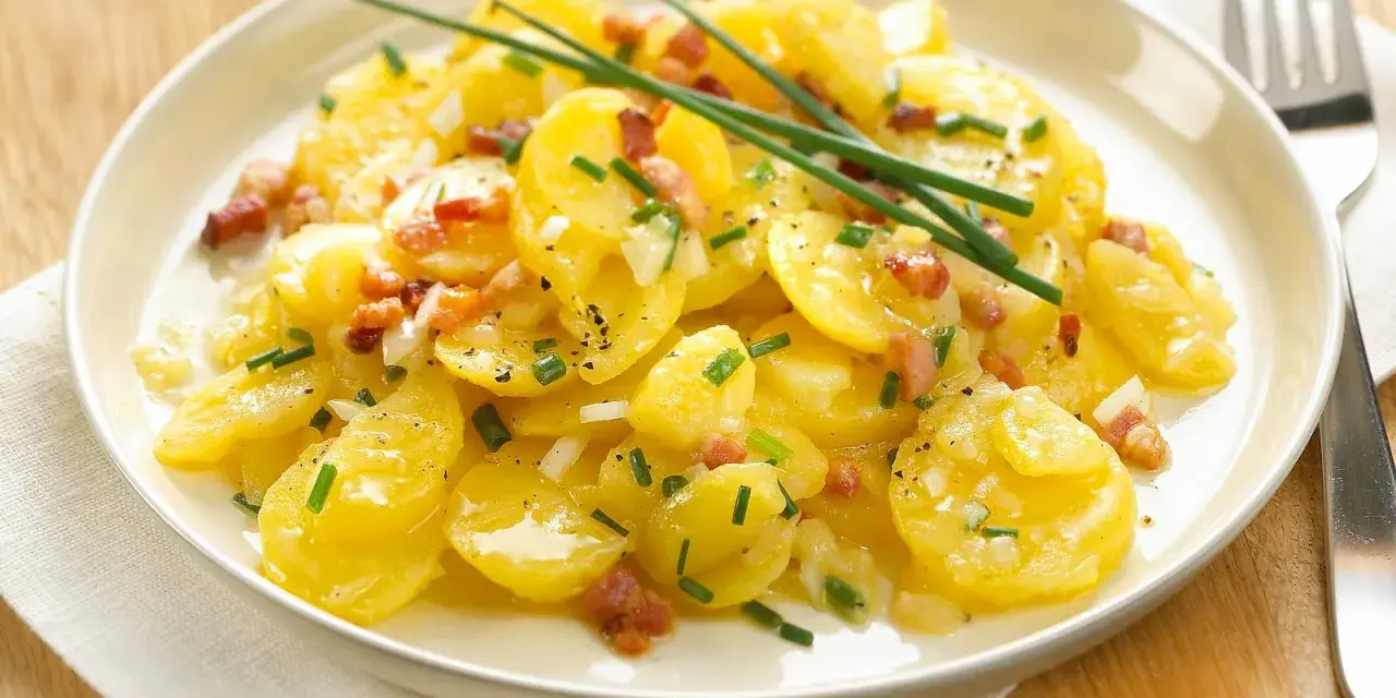 Ein Teller mit Kartoffelsalat mit Speck, garniert mit Schnittlauch. Ein Klassiker, der immer schmeckt.