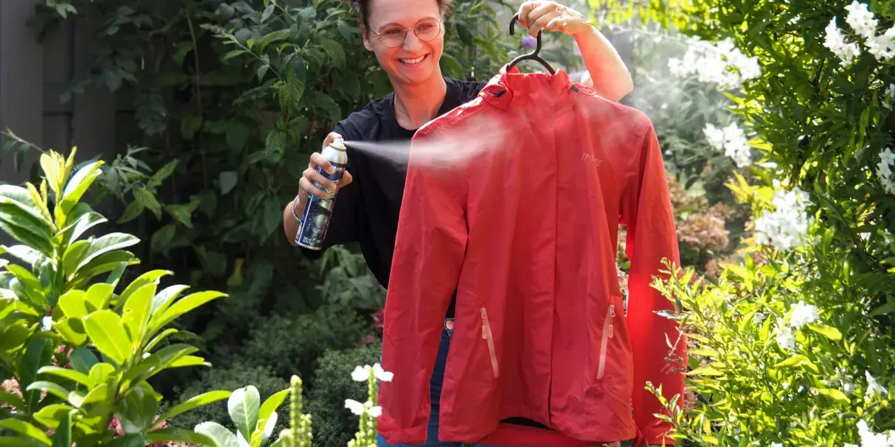 Frau sprüht rote Funktionskleidung ein, um sie für das Waschen vorzubereiten.