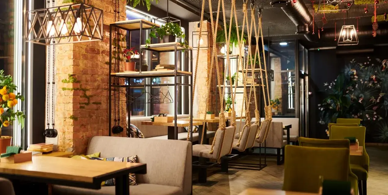 Un restaurante moderno con ladrillo visto, plantas colgantes y columpios. Un lugar acogedor que inspira lo que se necesita para abrir un restaurante.