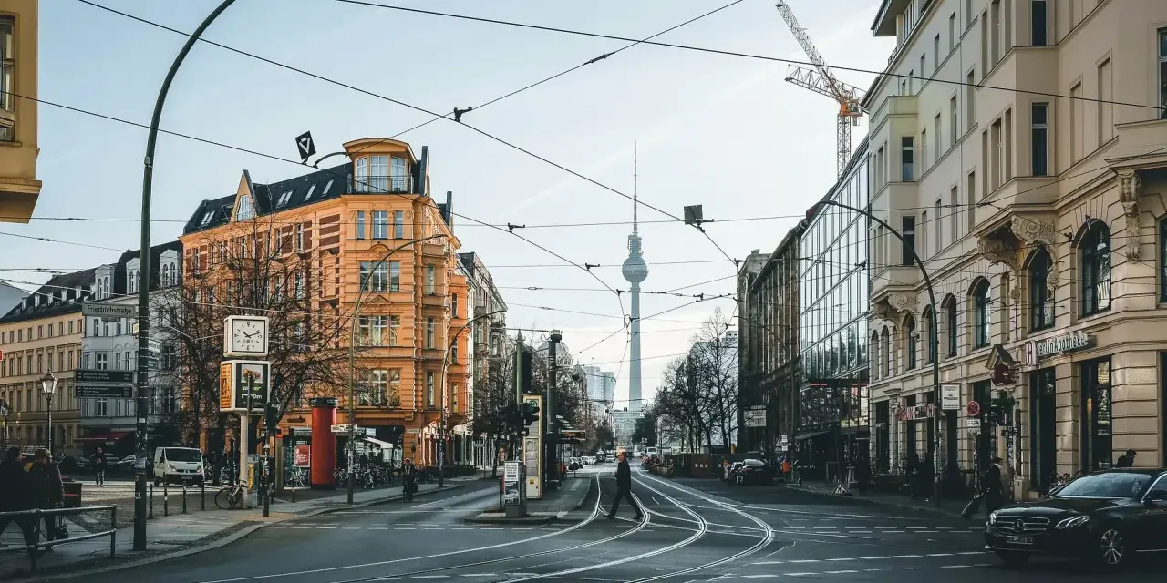 Skrzyżowanie w Berlinie z widoczną wieżą telewizyjną. Czy Berlin jest bezpieczny? Miasto tętni życiem, a ludzie swobodnie poruszają się po ulicach.