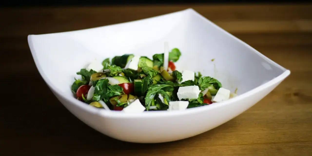 Salade fraîche et colorée avec des cubes de fromage pour salade, tomates cerises, concombres et olives vertes.