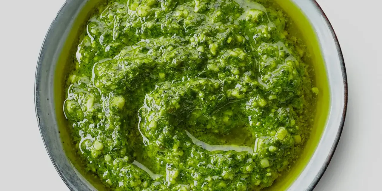 Närbild på hemmagjord pesto i en skål. Oljan flyter runt den gröna, grovhackade peston. Perfekt för att förlänga hållbarheten.
