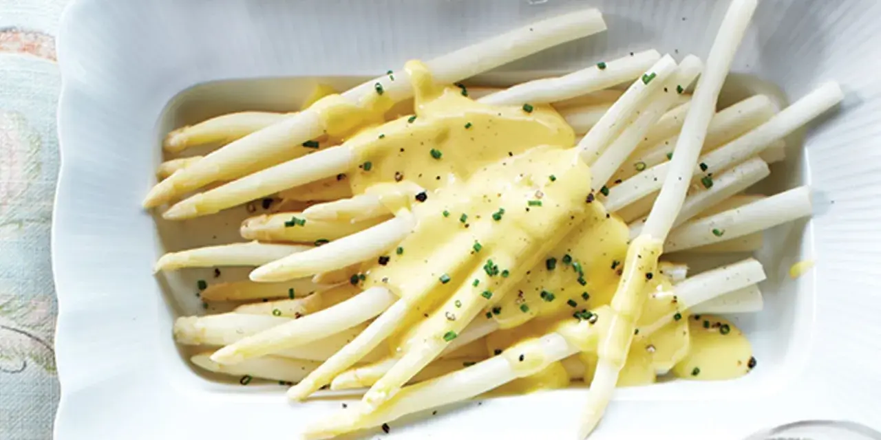 Asperges blanches nappées d'une sauce onctueuse, parsemées de ciboulette fraîche. Un délice printanier.