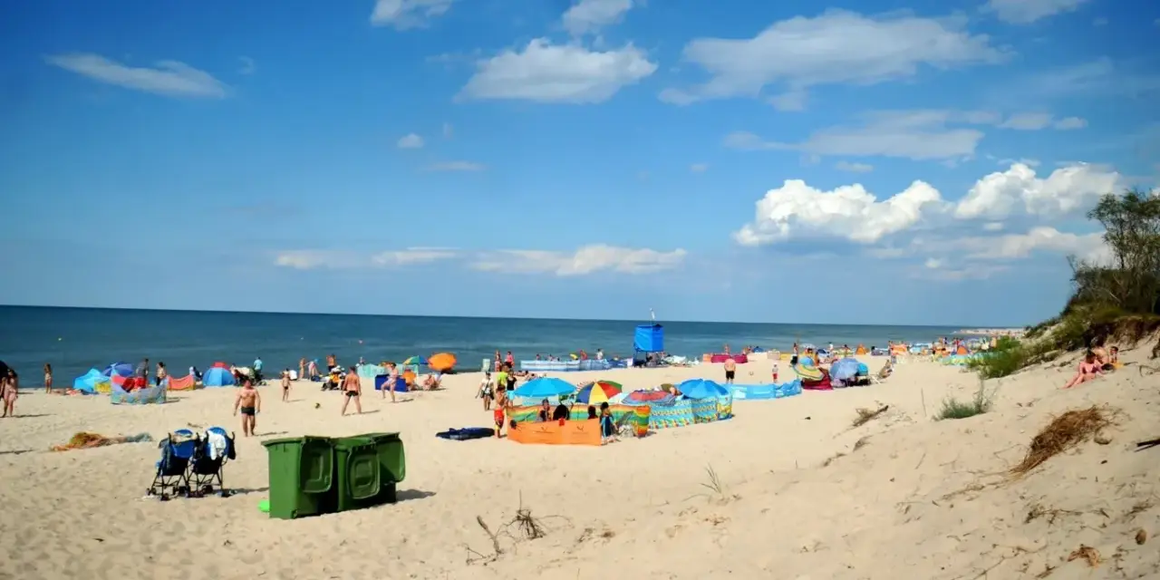Plaża pełna ludzi, kolorowe parawany i namioty. Idealne miejsce, gdzie ciepła woda w czerwcu zachęca do kąpieli.