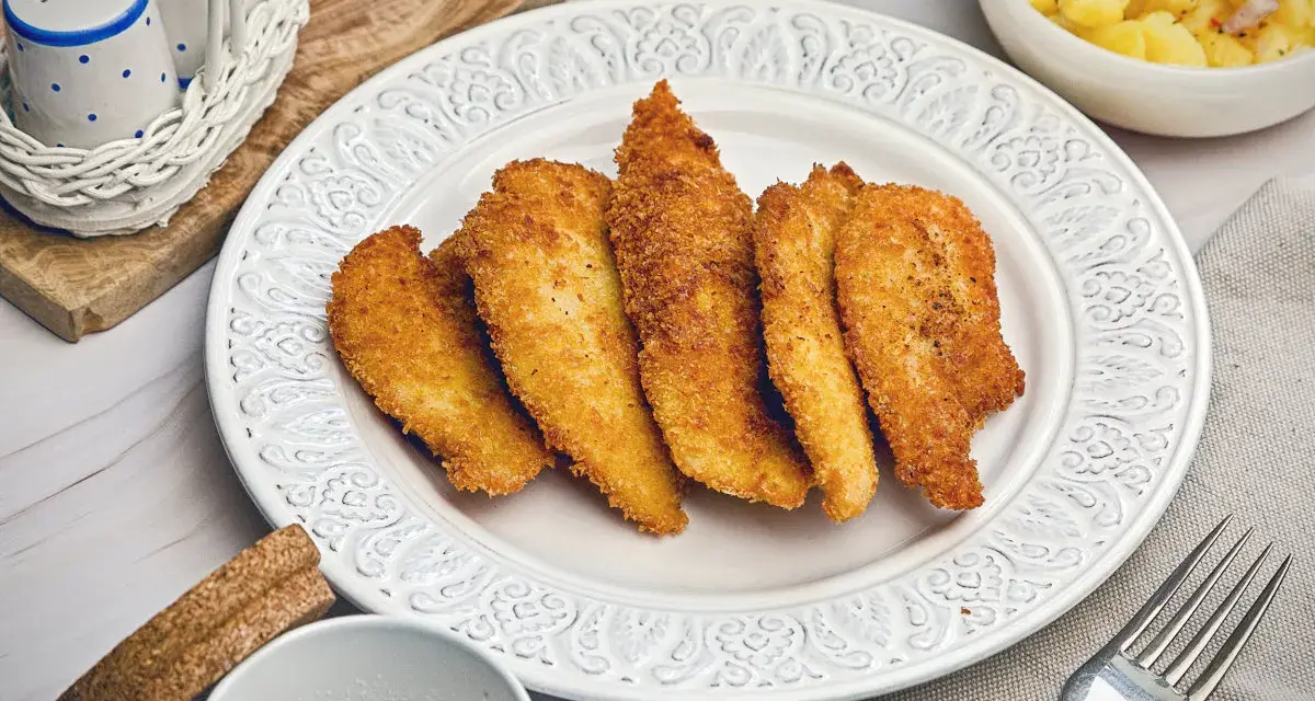 Knuspriges Wiener Backhendl, original Rezept. Goldbraun paniert und perfekt gegart, daneben Kartoffelsalat.