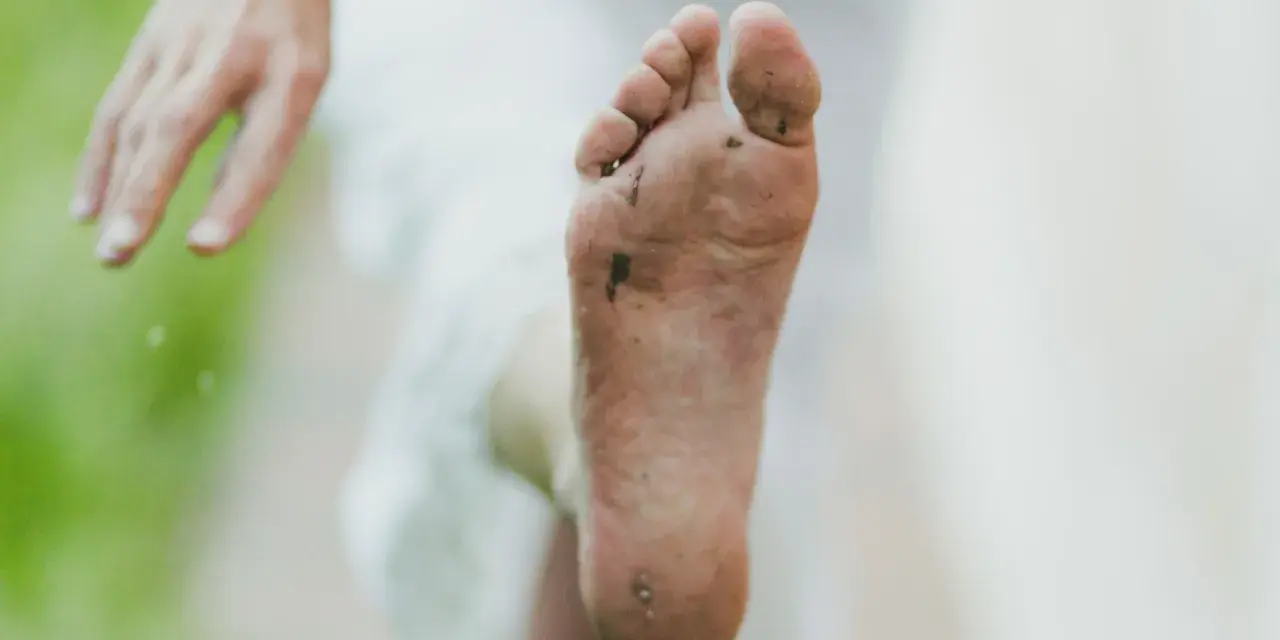 Pie sucio y descalzo, con tierra y hierba. Un consejo para como quitar el olor de los pies es lavarlos bien.