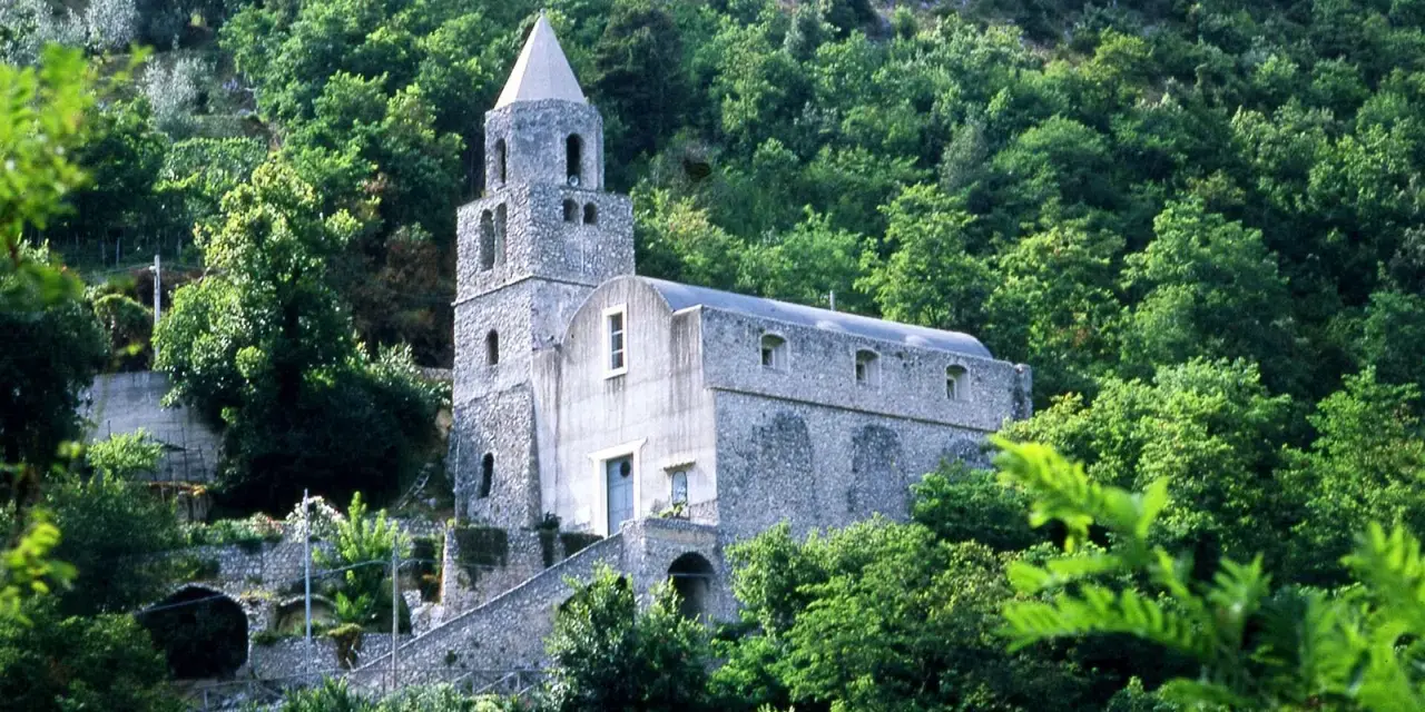 Antica chiesa in pietra su un fianco di montagna, circondata da alberi lussureggianti. I tramonti montagna qui sono magici.