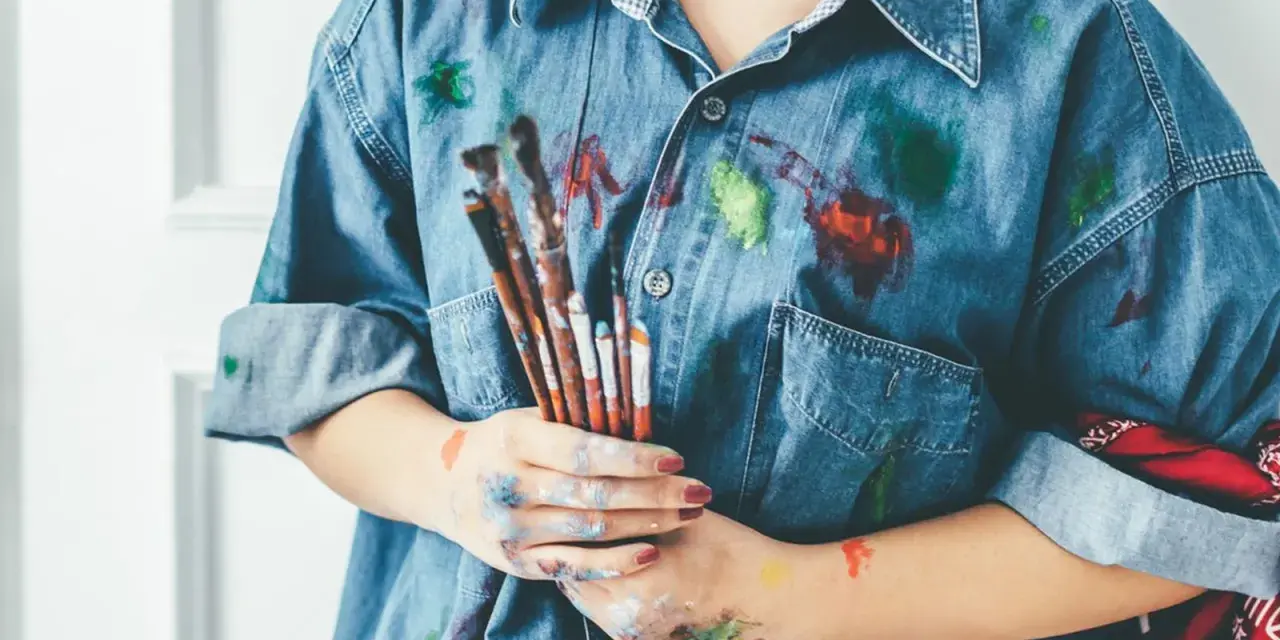 Manos manchadas de tempera y una camisa vaquera salpicada de pintura. ¡Un desafío para quitar tempera de la ropa!