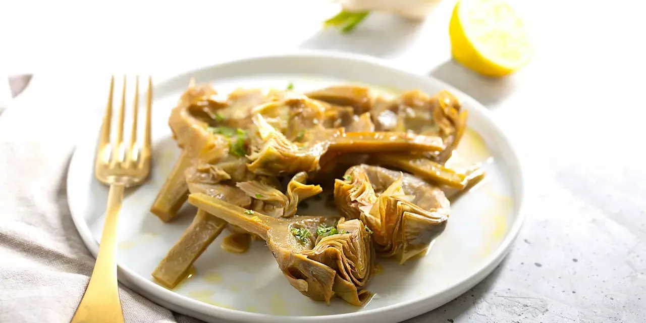Carciofi cotti in olio e limone, pronti per essere serviti. Scopri come congelare i carciofi per averli sempre a disposizione.