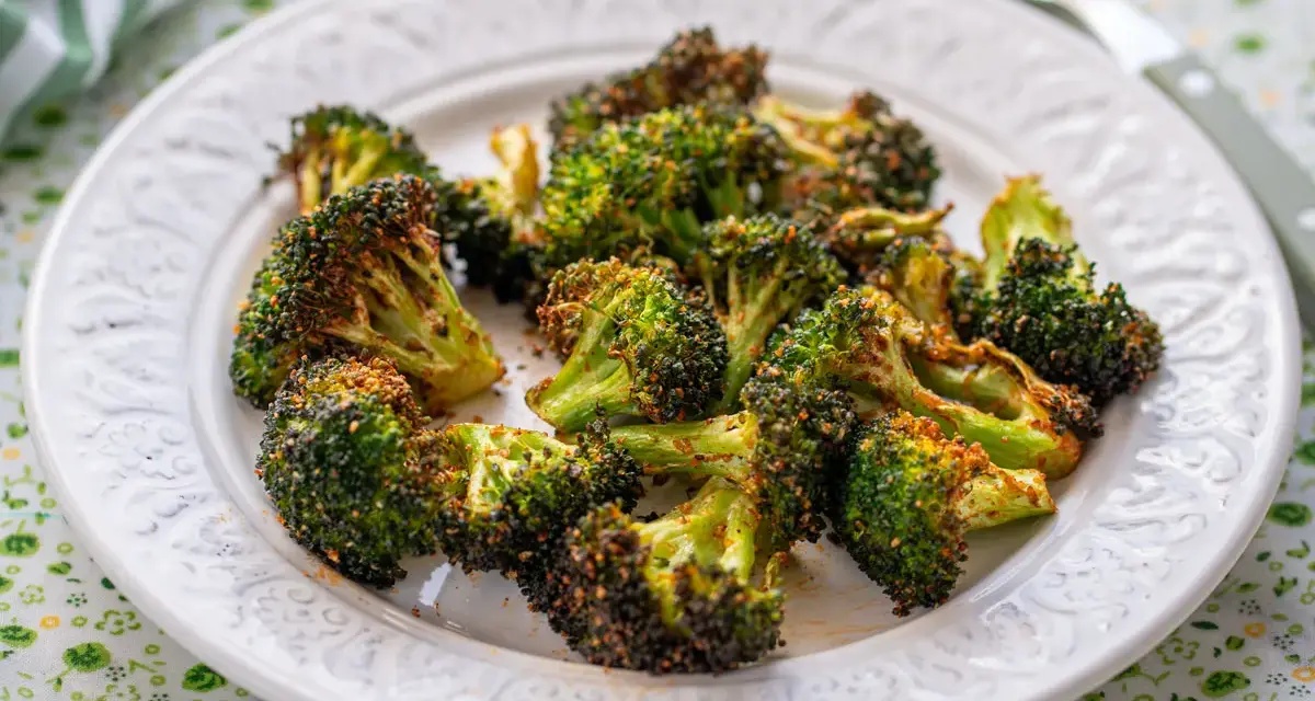 Brocoli en airfryer, crujiente y dorado, servido en un plato blanco con un mantel verde.