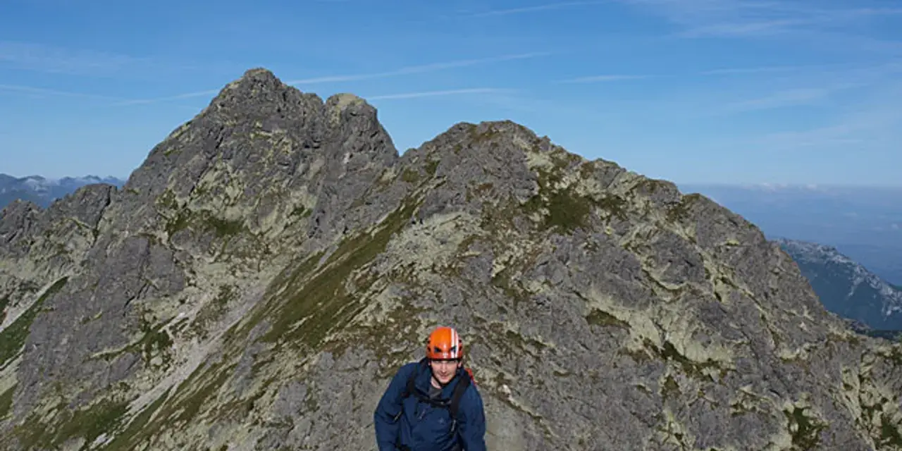 Turysta w kasku na skalistym szlaku Orlej Perci w Tatrach.