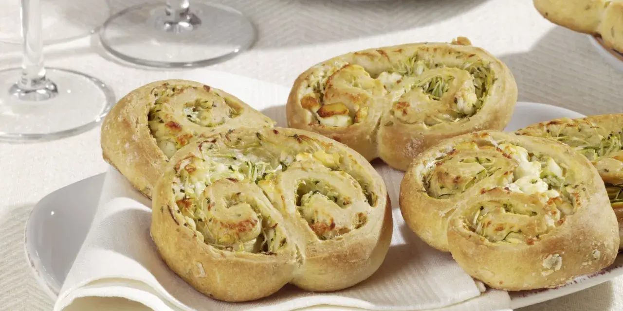 Zucchini Schnecken mit Käsefüllung auf einem Teller mit weißer Serviette.
