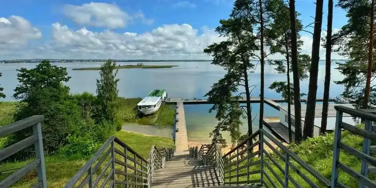 Idealne miejsce na weekend na Mazurach. Drewniane schody prowadzą do jeziora, gdzie cumuje statek.