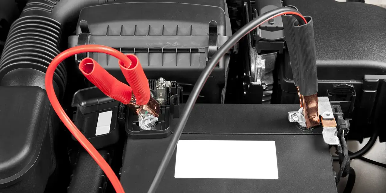 Jumper cables connected to a car battery. Learn how long to leave jumper cables on for a successful jump start.