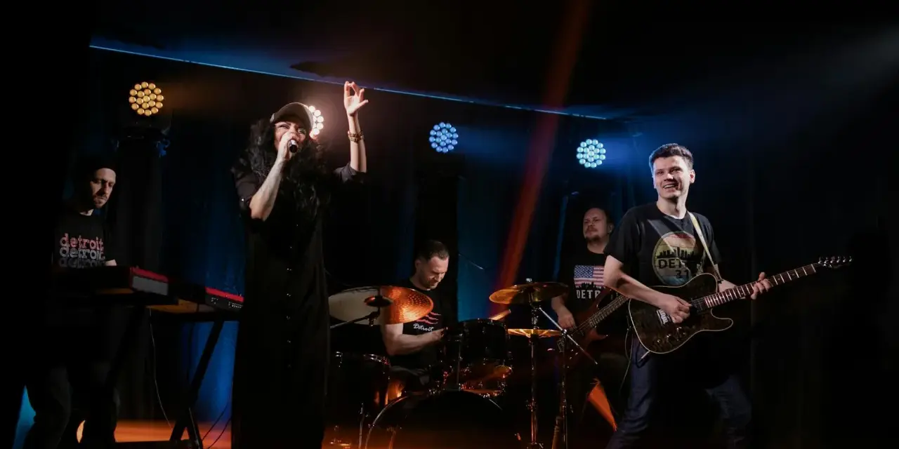 Zespół rockowy na scenie: wokalistka, gitarzysta, basista, perkusista i klawiszowiec. Koncert jak z listy zespoły rockowe zagraniczne alfabetycznie.