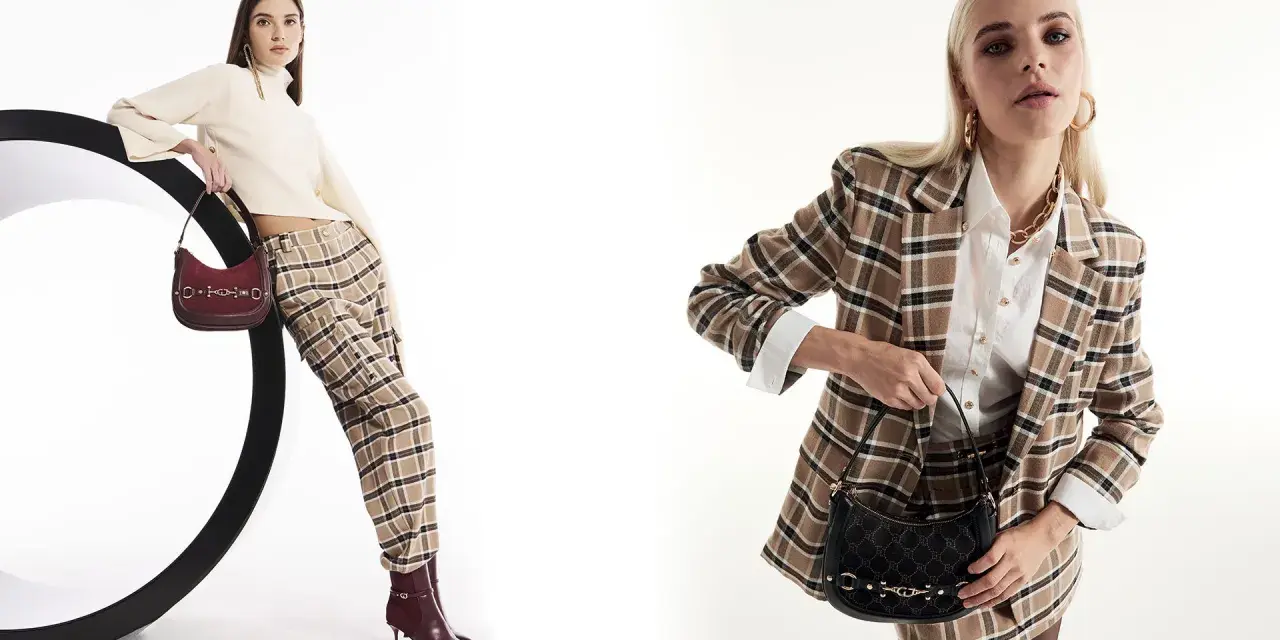 Due modelli mostrano idee outfit ufficio inverno: uno con maglione a collo alto, pantaloni a quadri e borsa bordeaux; l'altro con blazer a quadri, camicia bianca e borsa nera.