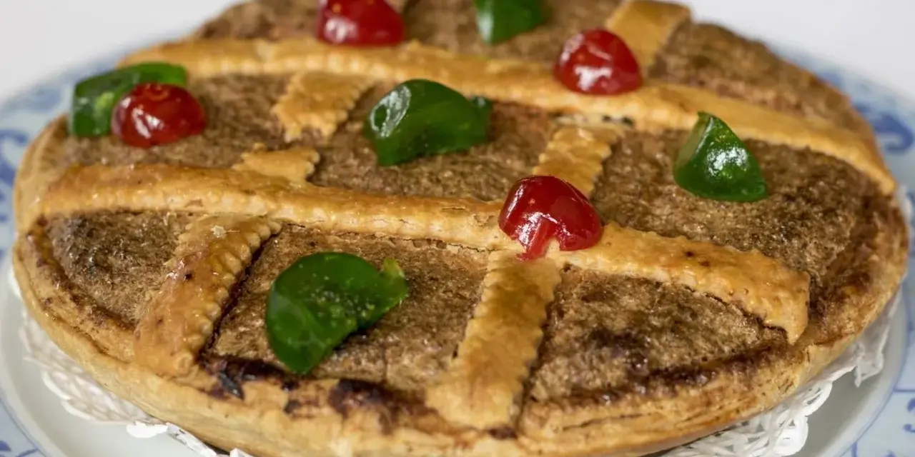 Tarta de Mondoñedo, un dulce tradicional con masa dorada, relleno de frutos secos y decorada con cerezas rojas y verdes.