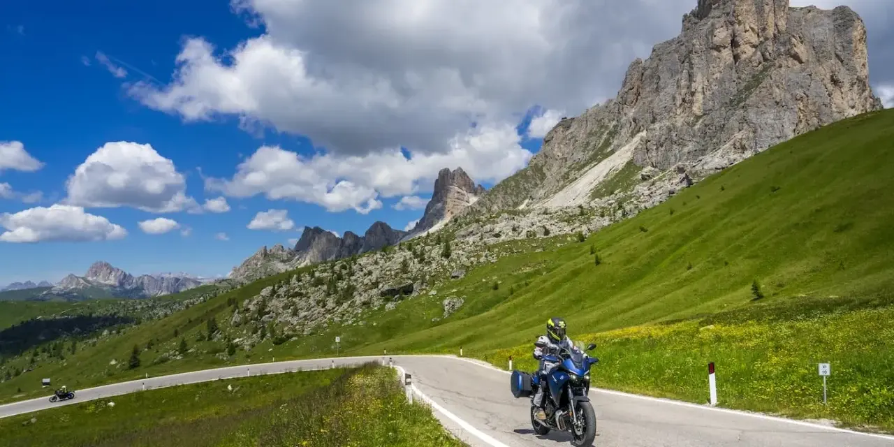 Motociclista su strada panoramica tra le montagne, un invito a scoprire le **strade da fare in moto** con panorami mozzafiato.