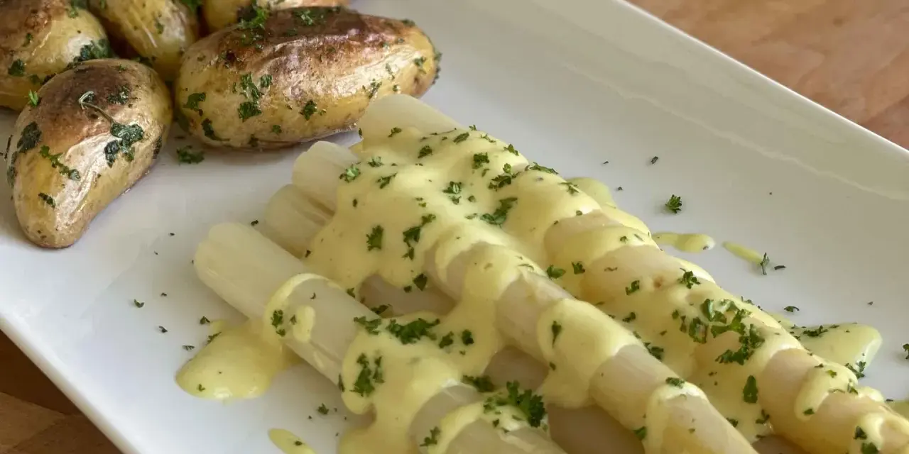 Weißer Spargel mit Kartoffeln und cremiger, veganer Hollandaise, bestreut mit frischer Petersilie. Ein Genuss!