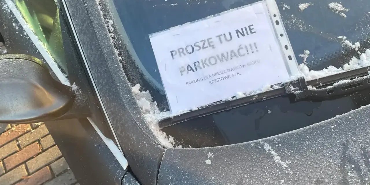 Na przedniej szybie samochodu, pokrytej szronem, widnieje kartka z napisem "Proszę tu nie parkować!!! Parking tylko dla mieszkańców bloku".