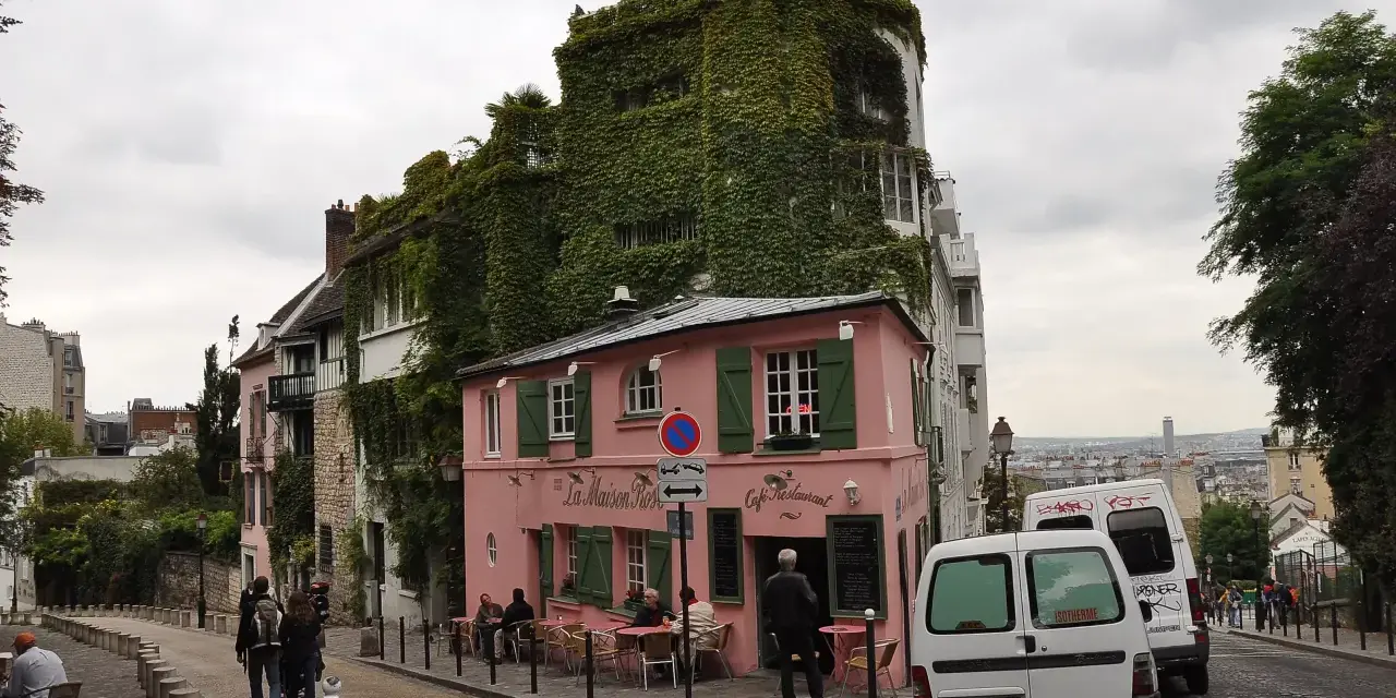 Urokliwa ulica na Montmartre z różową kawiarnią La Maison Rose i budynkiem porośniętym bluszczem.