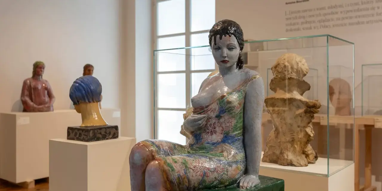 Ceramiczna rzeźba kobiety w kwiecistej sukni, dzieło inspirowane twórczością Olgi Niewskiej, prezentowana w muzeum.