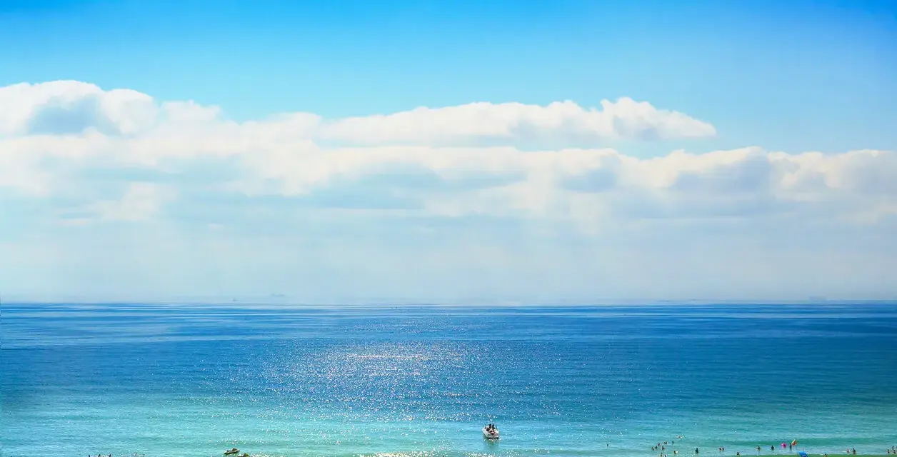 Słoneczna plaża w Bułgarii, idealna na wrzesień. Temperatura wody i powietrza zachęca do kąpieli i relaksu pod parasolami.