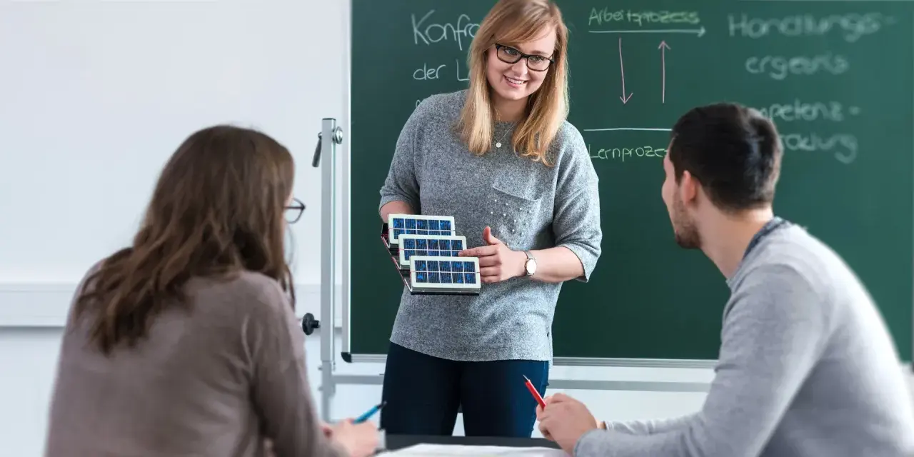 Lehrerin erklärt Schülern, wie man Berufsschullehrer wird, mit Solarzellen-Modell.