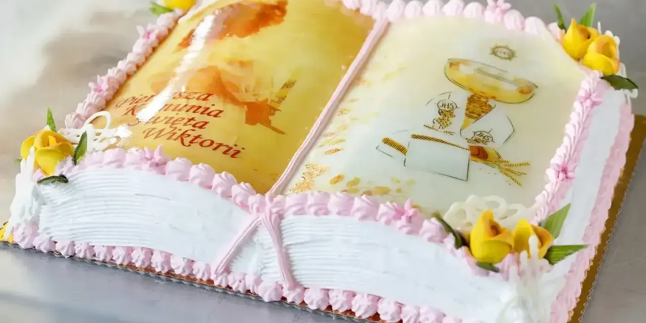 Eleganckie ciasto na komunię w kształcie otwartej księgi z motywami religijnymi i napisem "Pierwsza Komunia Święta Wiktorii".