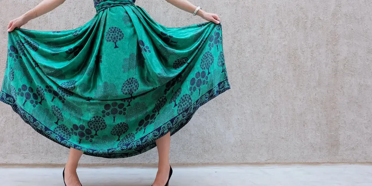 Abito color ottanio con fantasia di alberi. Scarpe nere eleganti completano il look.