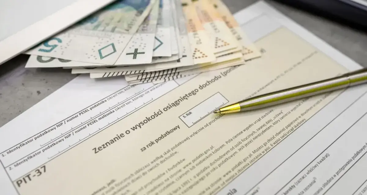Pieniądze i formularz PIT-37. Zastanawiasz się, jaka jest kwota wolna od podatku? Długopis czeka na wypełnienie zeznania.